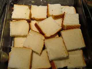 Slices of bread arranged in buttered baking dish.